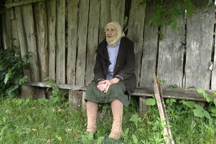 A 102-year-old woman smiles as she celebrates her birthday surrounded by family.